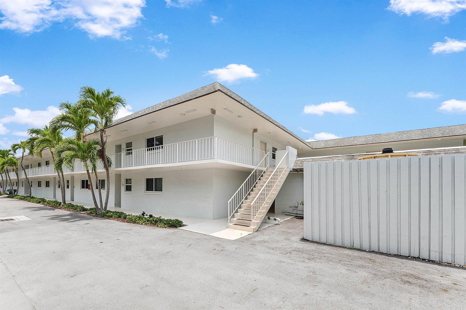 A two-story apartment building with a white exterior, palm trees, and an external staircase — 207 Tropic Isle Drive # 2050, Delray Beach FL 33483, DELRAY BEACH, FL