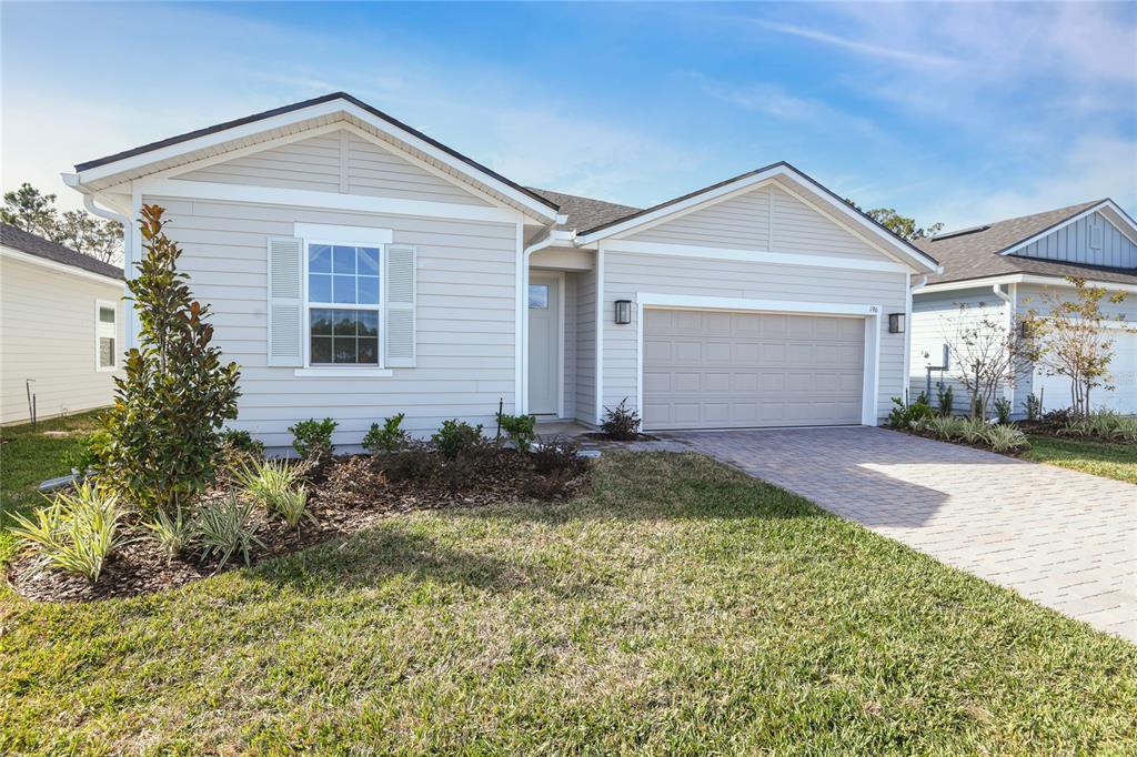 A single-story house with light-colored siding, a two-car garage, and a paved driveway — 196 ENCLAVE AVENUE, PALM COAST, FL
