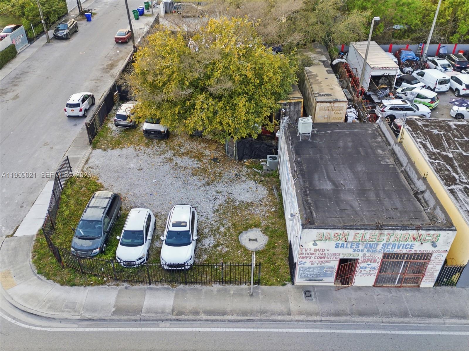 An aerial view shows a commercial building with a gravel lot and several parked cars — 7004 NW 7th Ave, Miami FL 33150, MIAMI, FL