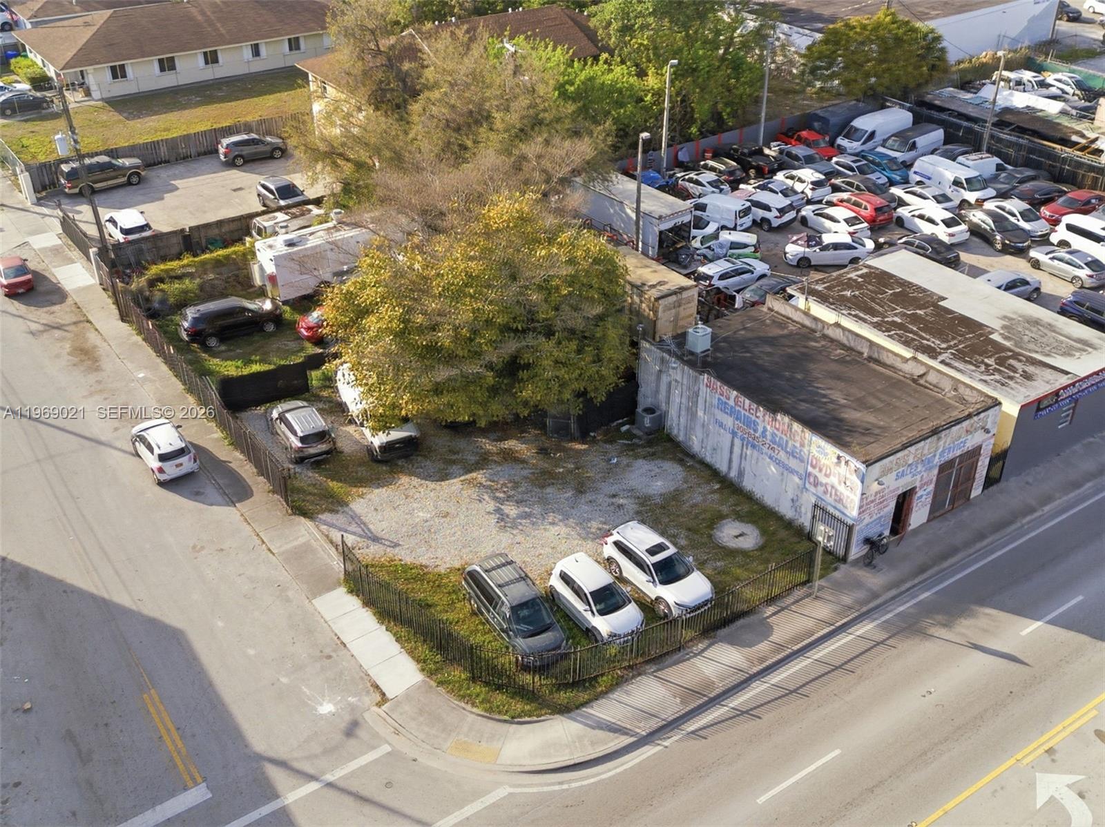 An aerial view shows a commercial building with a fenced parking lot and many vehicles — 7004 NW 7th Ave, Miami FL 33150, MIAMI, FL