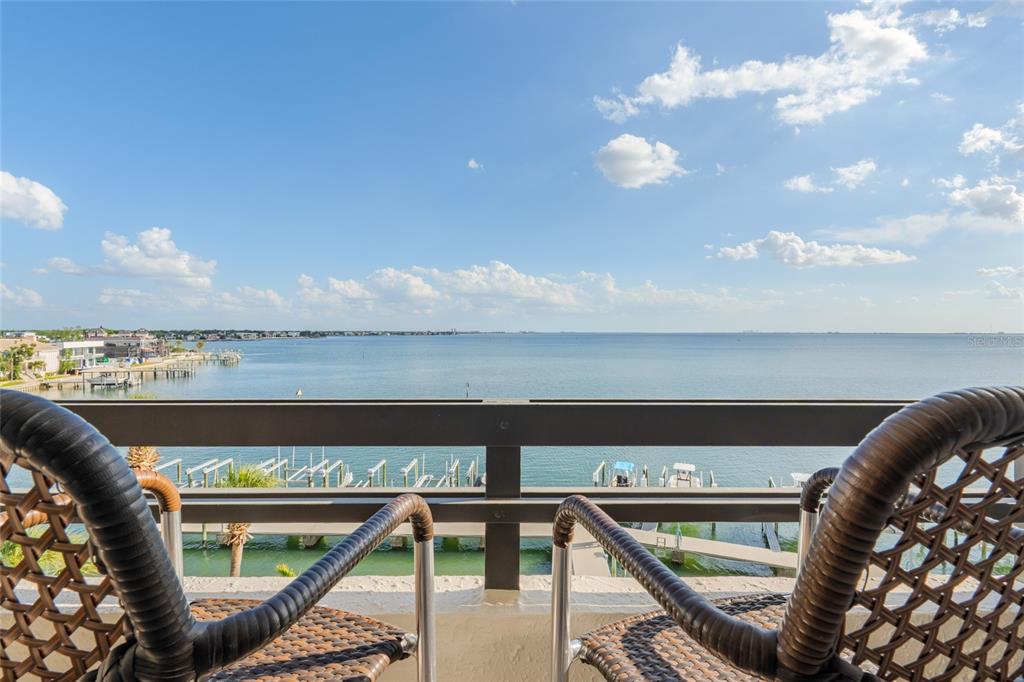 A balcony with two wicker chairs overlooks a wide bay with docks and houses — 5700 MARINER STREET UNIT 503A, TAMPA, FL