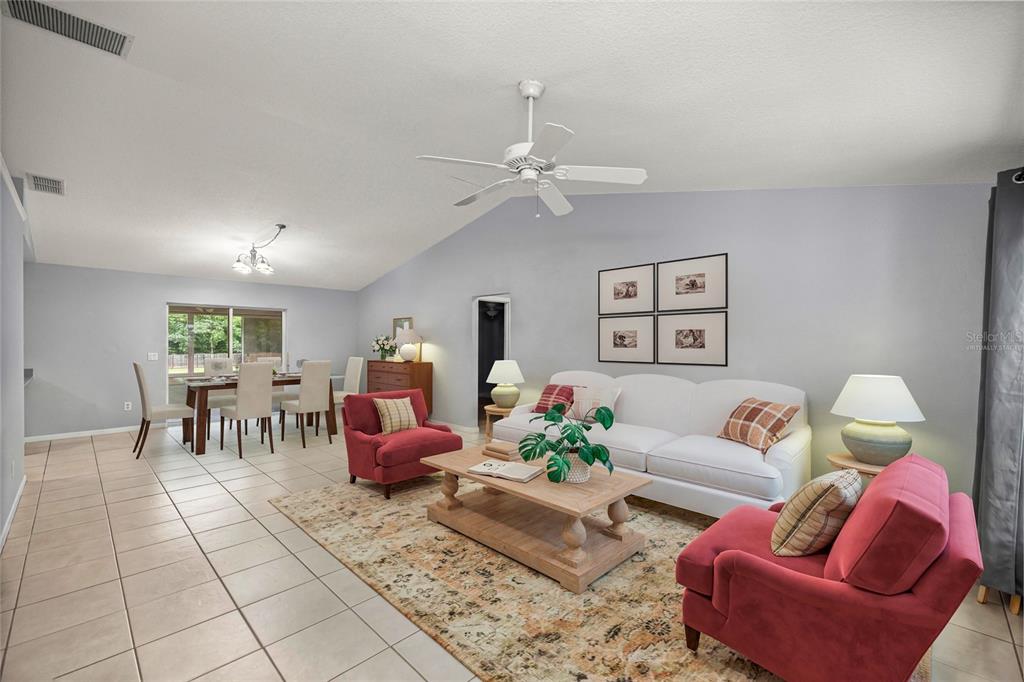 A living room with a white sofa, two red armchairs, and an adjacent dining area — 13980 SE 53RD AVENUE, SUMMERFIELD, FL