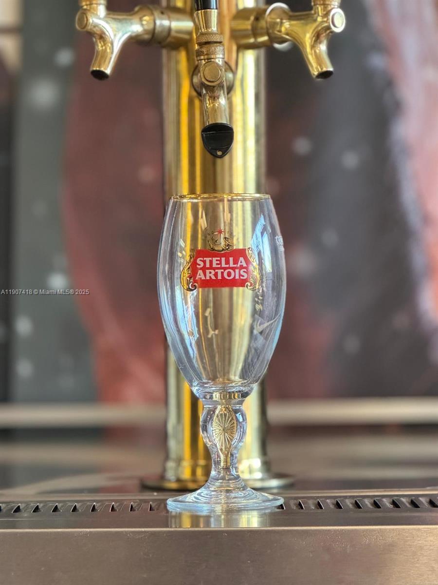 A Stella Artois beer glass sits on a metal counter in front of beer taps — 6827 Stirling, Davie FL 33314, DAVIE, FL