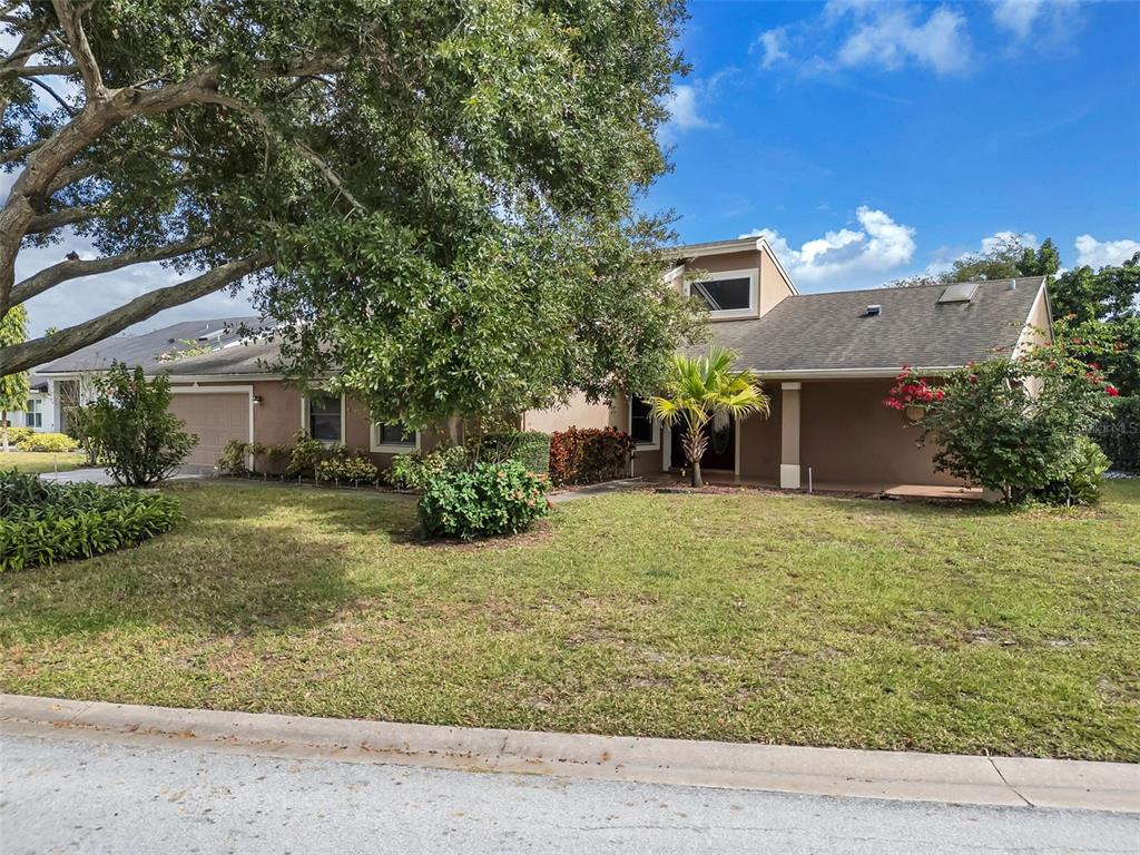 A tan two-story house with a garage and a large tree in the front yard — 6047 SHORE LINE DRIVE, ORLANDO, FL