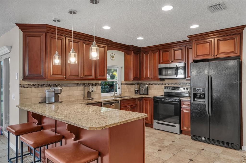 A kitchen with wood cabinets, granite countertops, stainless steel appliances, and a breakfast bar — 6047 SHORE LINE DRIVE, ORLANDO, FL