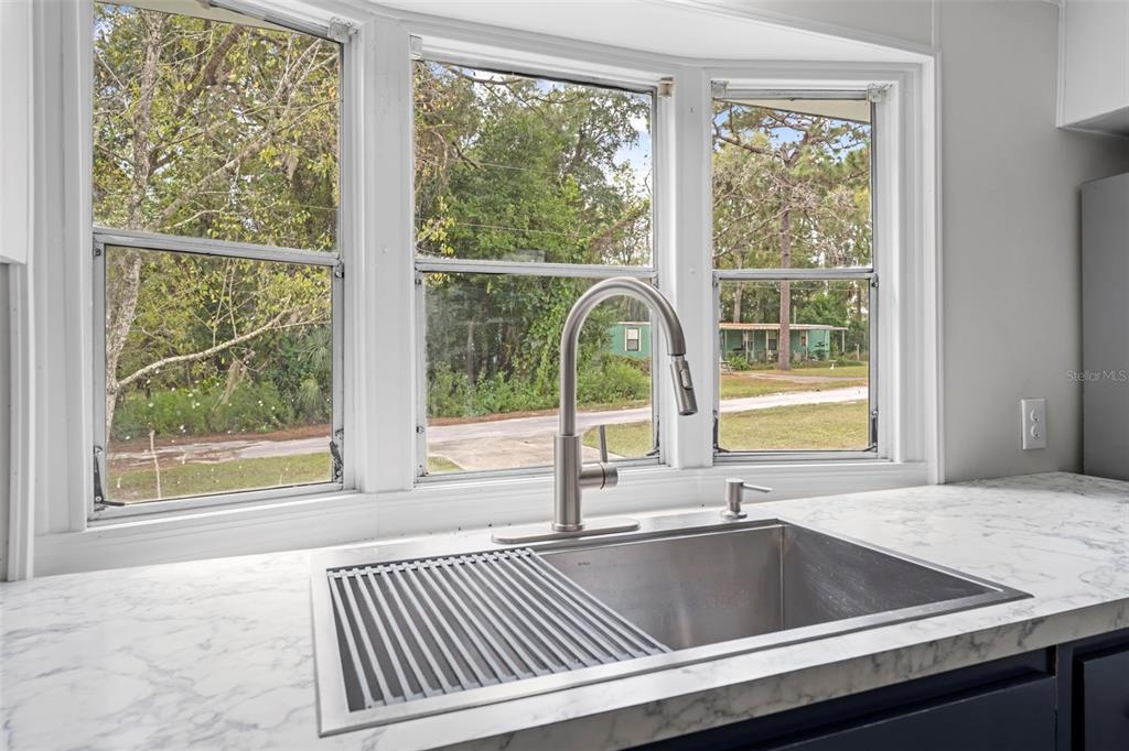 A kitchen sink with a metal faucet sits before a bay window overlooking a yard — 8061 W ROSELLA COURT, CRYSTAL RIVER, FL