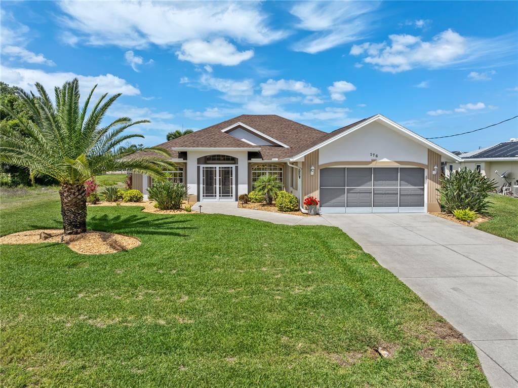 A single-story house with a palm tree, a concrete driveway, and a two-car garage — 176 MARINER LANE, ROTONDA WEST, FL