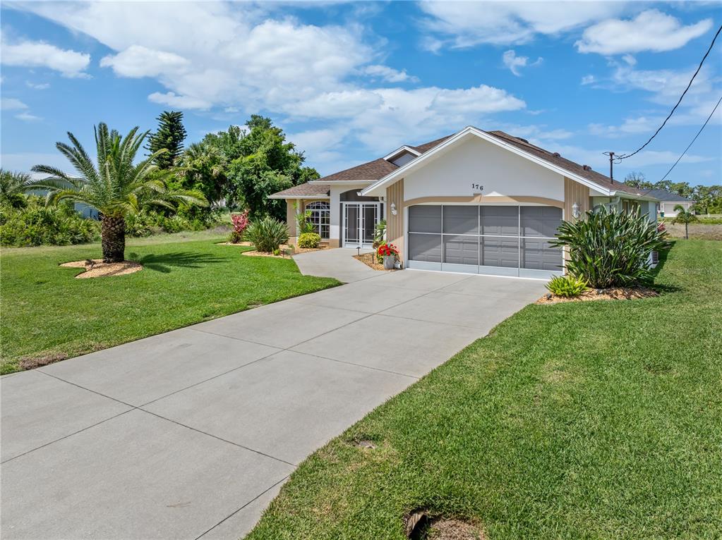 A single-story house with a concrete driveway, a two-car garage, and a palm tree — 176 MARINER LANE, ROTONDA WEST, FL