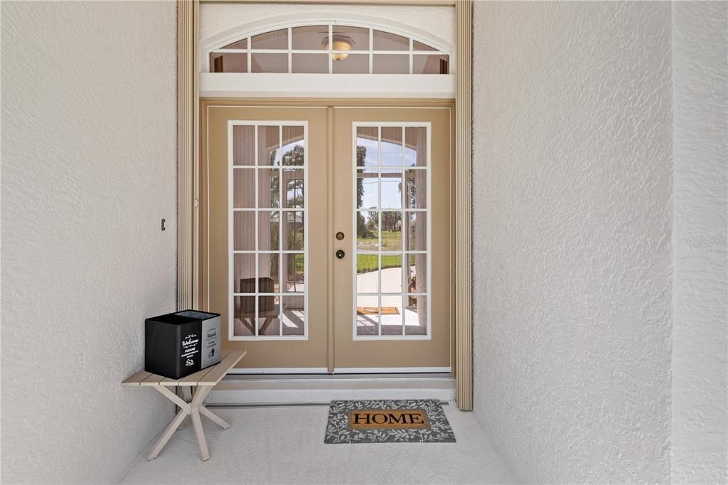 A tan double door with glass panes sits under an arched transom window — 176 MARINER LANE, ROTONDA WEST, FL