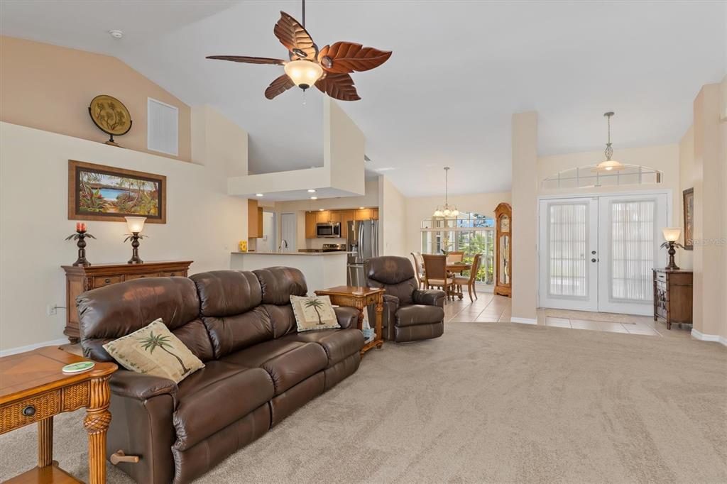 A living room with brown leather furniture, a ceiling fan, and an open kitchen area — 176 MARINER LANE, ROTONDA WEST, FL