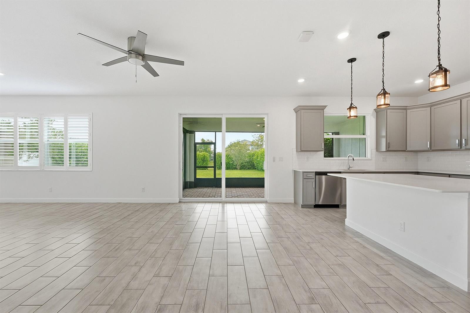 An open-concept kitchen and living area features light wood-look tile floors and sliding glass doors — 1261 Deer Hvn Drive, Loxahatchee FL 33470, LOXAHATCHEE, FL