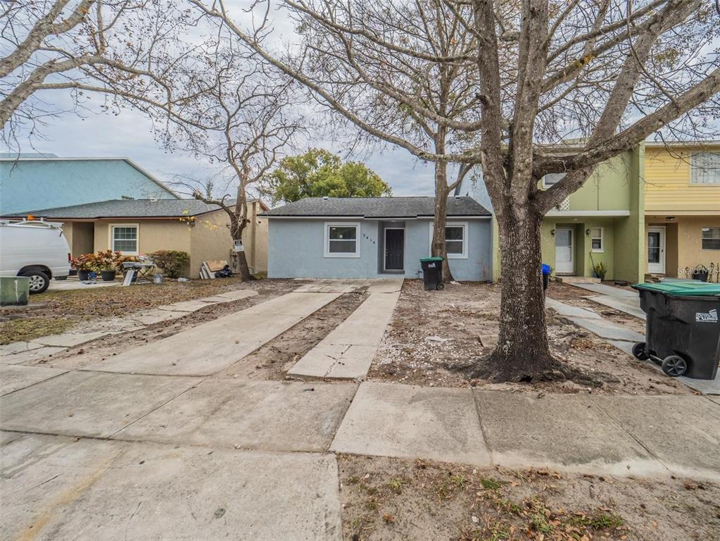 A light blue single-story house with a concrete driveway and a large tree in front — 2419 RIO PINAR LAKES BOULEVARD, ORLANDO, FL
