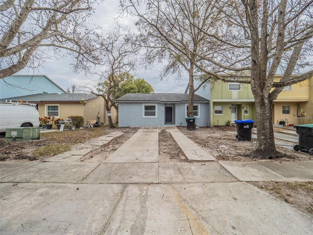 A single-story light blue house with a concrete driveway sits between two other residential buildings — 2419 RIO PINAR LAKES BOULEVARD, ORLANDO, FL
