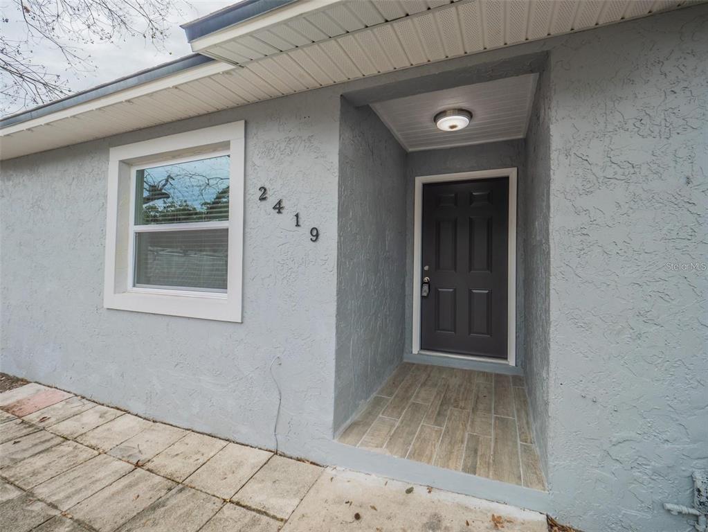 The exterior of a house features a gray stucco wall, a dark door, and tiled entryway — 2419 RIO PINAR LAKES BOULEVARD, ORLANDO, FL