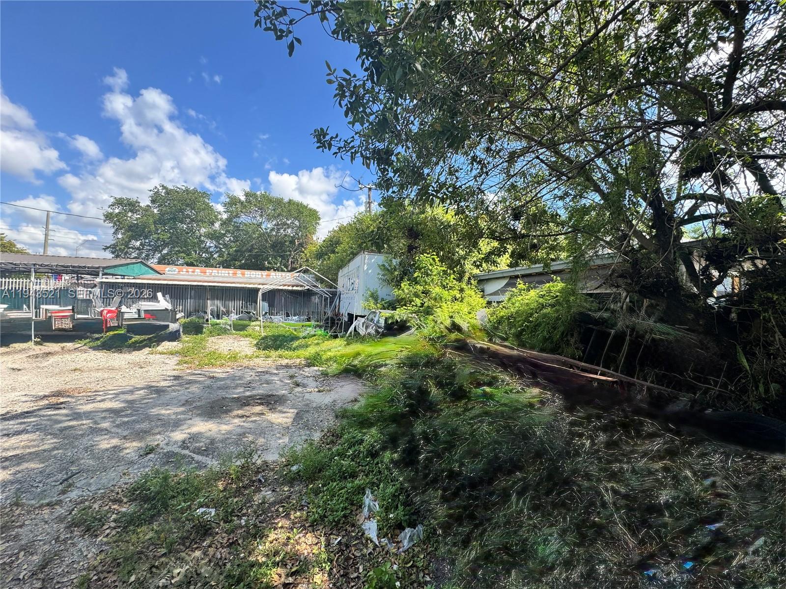 An outdoor lot features a gravel area, overgrown vegetation, and a nearby auto body shop — 6501 NW 7th Ave, Miami FL 33150, MIAMI, FL