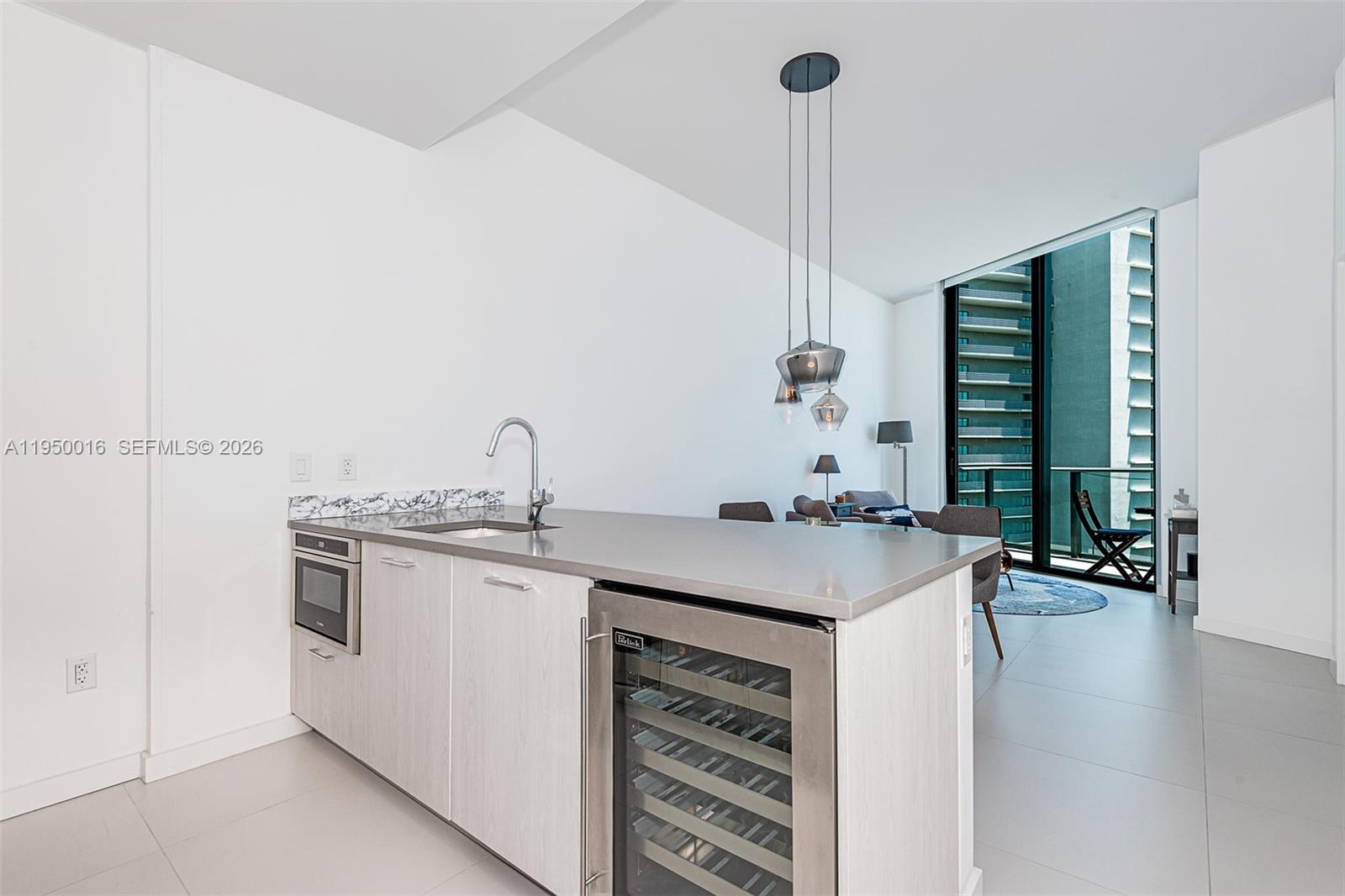 A modern kitchen island with a wine cooler and sink sits in a bright apartment — 501 NE 31st St, Miami FL 33137, MIAMI, FL