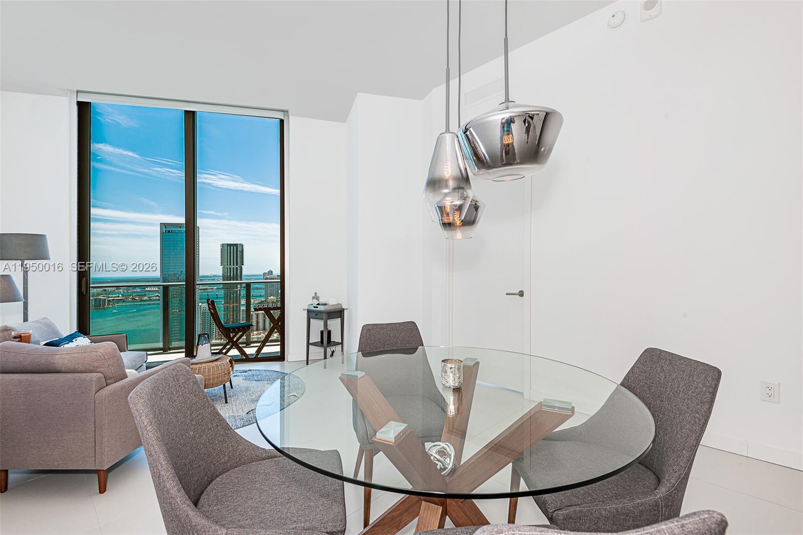 A dining area with a glass table and modern pendant lights overlooks a city skyline — 501 NE 31st St, Miami FL 33137, MIAMI, FL