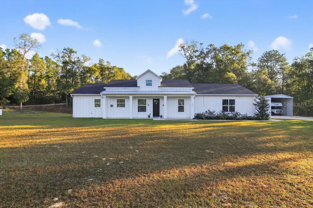 A white farmhouse-style house with a covered front porch sits on a large grassy lot — 5859 SW 129TH TERRACE ROAD, OCALA, FL