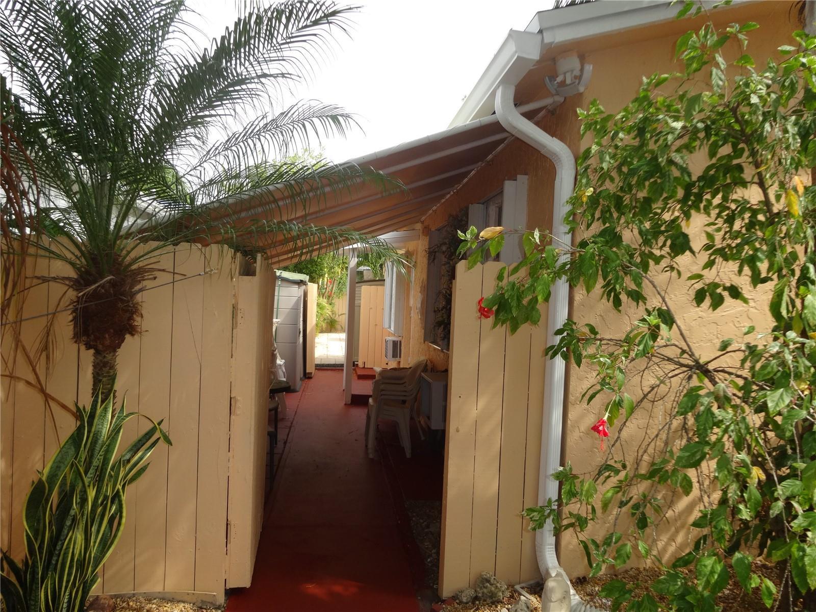A narrow outdoor walkway with a covered roof leads between a house and a fence — 31 SE 13th Street # 2, Dania Beach FL 33004, DANIA BEACH, FL