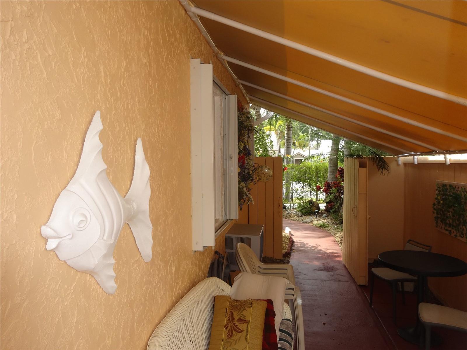 A covered outdoor patio features a white fish wall decoration, seating, and a small table — 31 SE 13th Street # 2, Dania Beach FL 33004, DANIA BEACH, FL