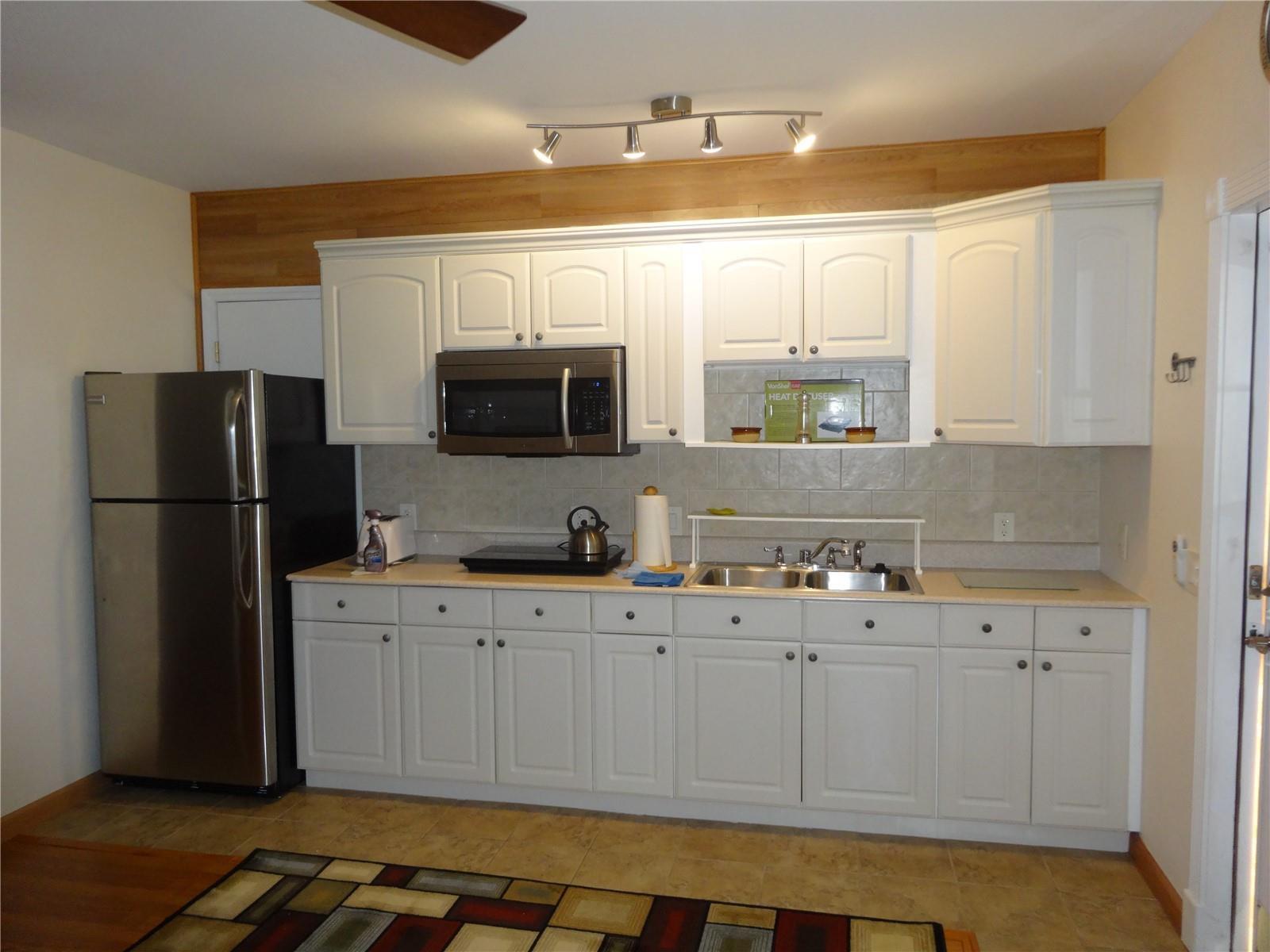 A kitchen features white cabinets, stainless steel appliances, a tile backsplash, and wood-paneled walls — 31 SE 13th Street # 2, Dania Beach FL 33004, DANIA BEACH, FL