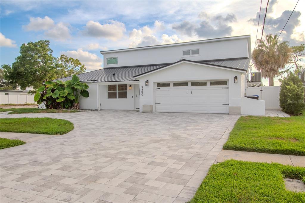 A white two-story house with a metal roof and a paved driveway — 5400 DENVER STREET NE, ST PETERSBURG, FL