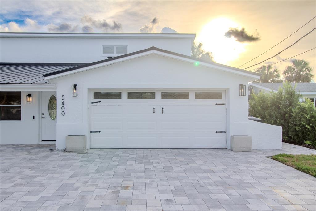 A white house exterior features a two-car garage, a front door, and a paved driveway — 5400 DENVER STREET NE, ST PETERSBURG, FL