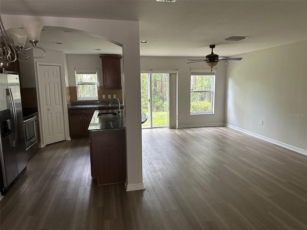 An open-concept kitchen with dark cabinets and an island overlooks a spacious living area — 2800 BIRCHCREEK DRIVE, WESLEY CHAPEL, FL