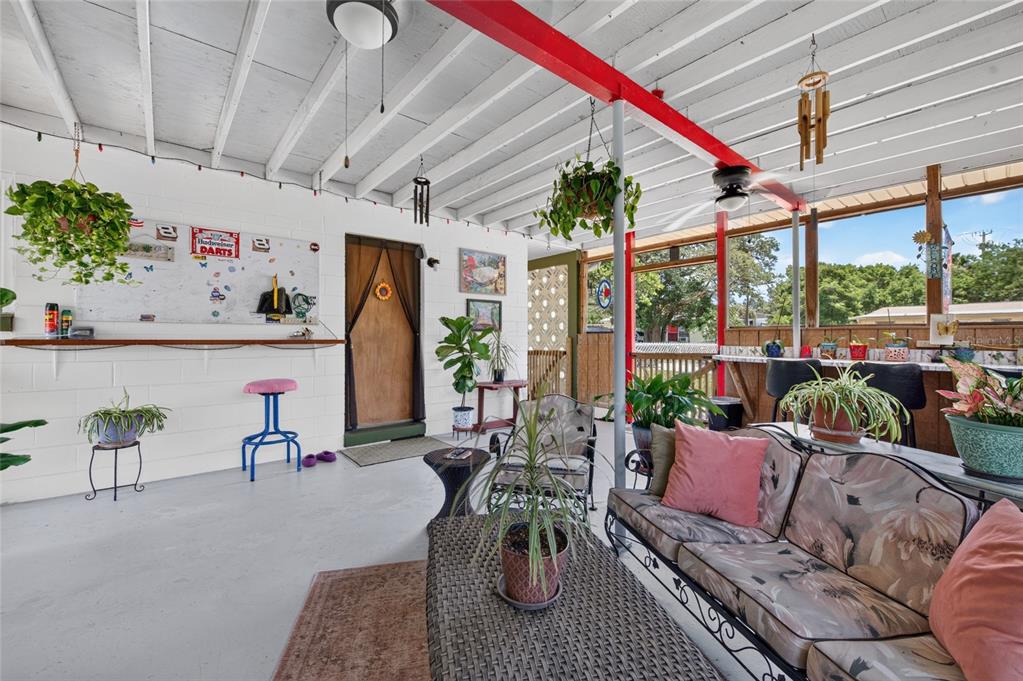 A covered patio features a concrete floor, white painted brick walls, and a seating area — 6 HIGHRIDGE ROAD, DAYTONA BEACH, FL