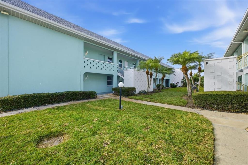 A light blue two-story apartment building with a grassy lawn and palm trees — 611 GULF DRIVE N UNIT C29, BRADENTON BEACH, FL