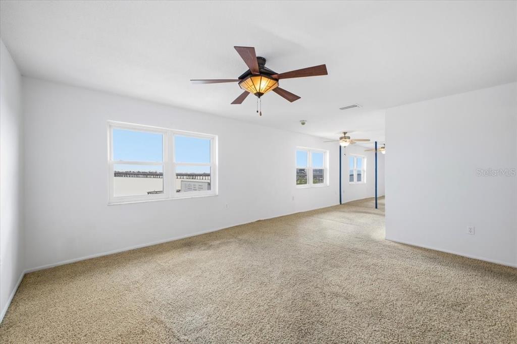 An empty room with beige carpet, white walls, and three ceiling fans — 611 GULF DRIVE N UNIT C29, BRADENTON BEACH, FL