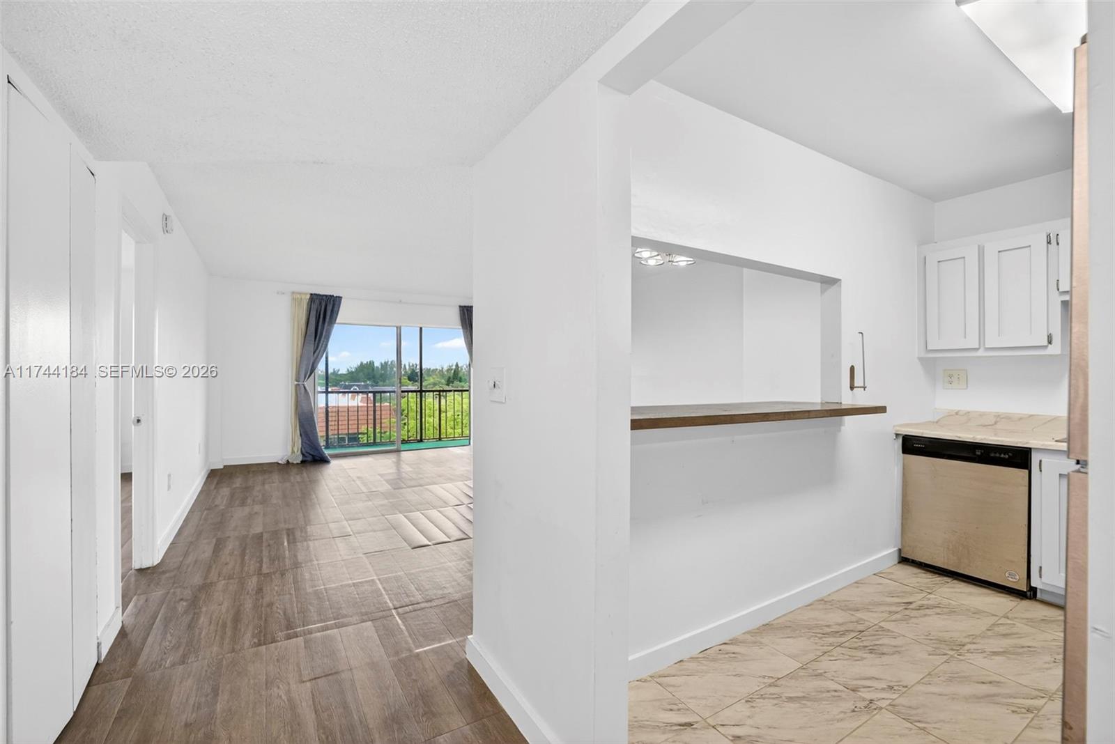 A kitchen with a breakfast bar opens into a living area with a balcony view — 4174 Inverrary Drive # 706, Lauderhill FL 33319, LAUDERHILL, FL