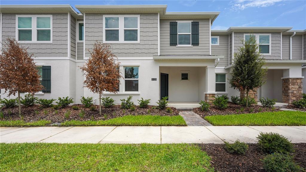 A two-story townhouse exterior features gray siding, white stucco, and a covered front entryway — 5120 CLAY WHALEY ROAD, ST CLOUD, FL