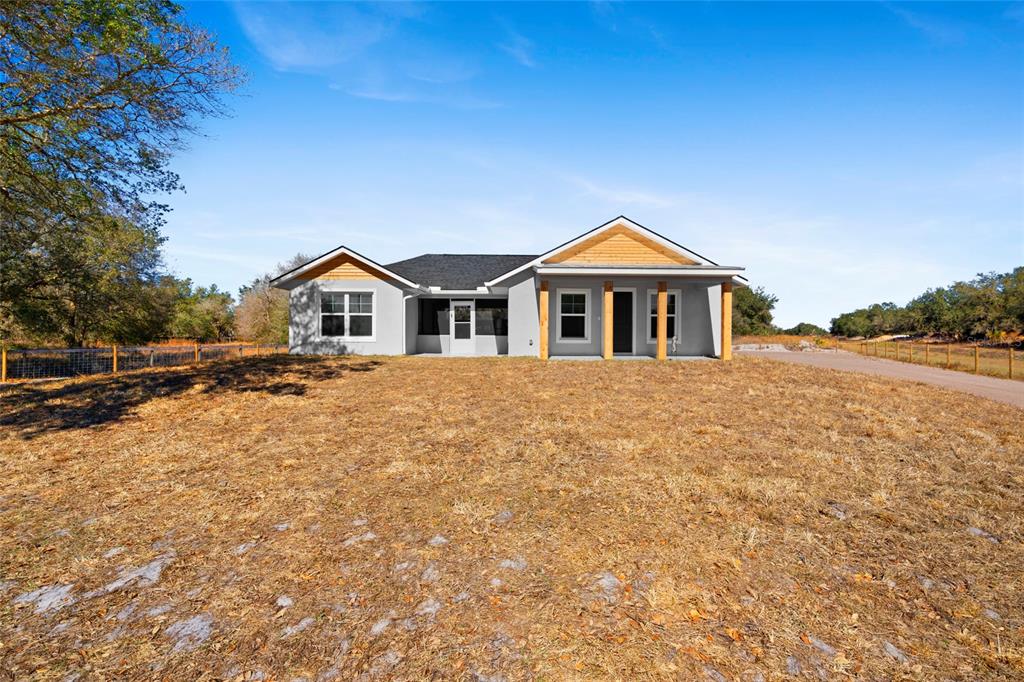 A single-story house with a light gray exterior, wood accents, and a covered front porch — 20806 NW 274TH STREET, OKEECHOBEE, FL