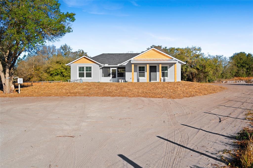 A single-story house with gray siding, a dark roof, and a covered front porch — 20806 NW 274TH STREET, OKEECHOBEE, FL