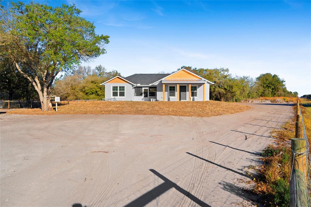 A single-story house with a gray exterior and wood accents sits on a dirt lot — 20806 NW 274TH STREET, OKEECHOBEE, FL