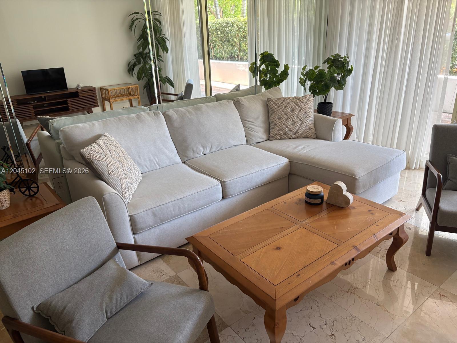 A living room features a light gray sectional sofa, a wooden coffee table, and armchairs — 199 Ocean Lane Dr # 113, Key Biscayne FL 33149, KEY BISCAYNE, FL
