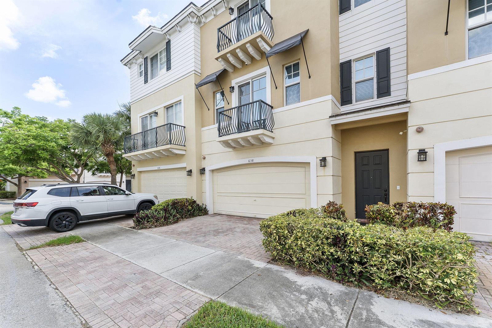 A multi-story townhouse exterior features a two-car garage, balconies, and a paved driveway — 638 NW 38th Circle, Boca Raton FL 33431, BOCA RATON, FL