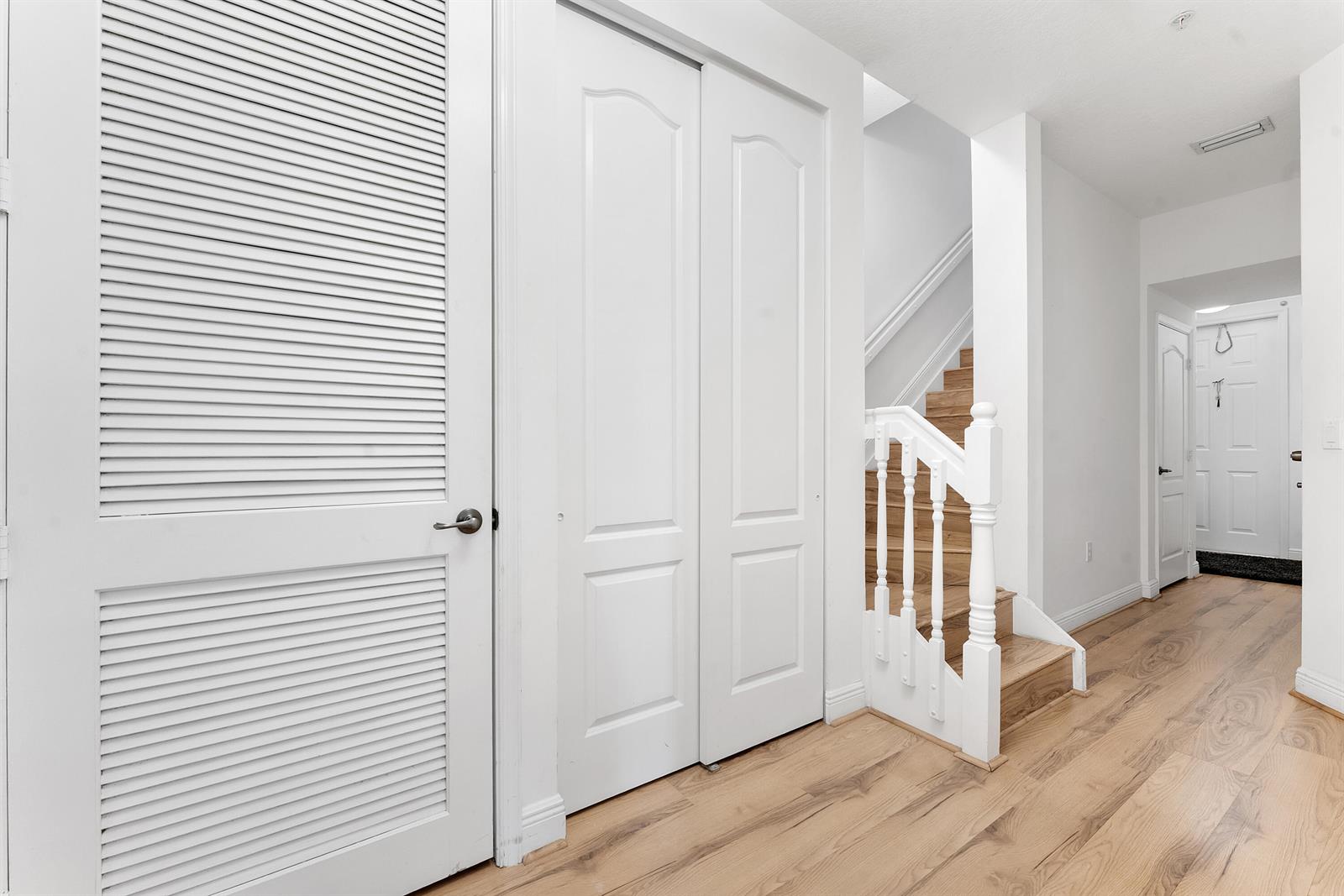 A hallway features white doors, a wooden staircase with a white railing, and hardwood flooring — 638 NW 38th Circle, Boca Raton FL 33431, BOCA RATON, FL