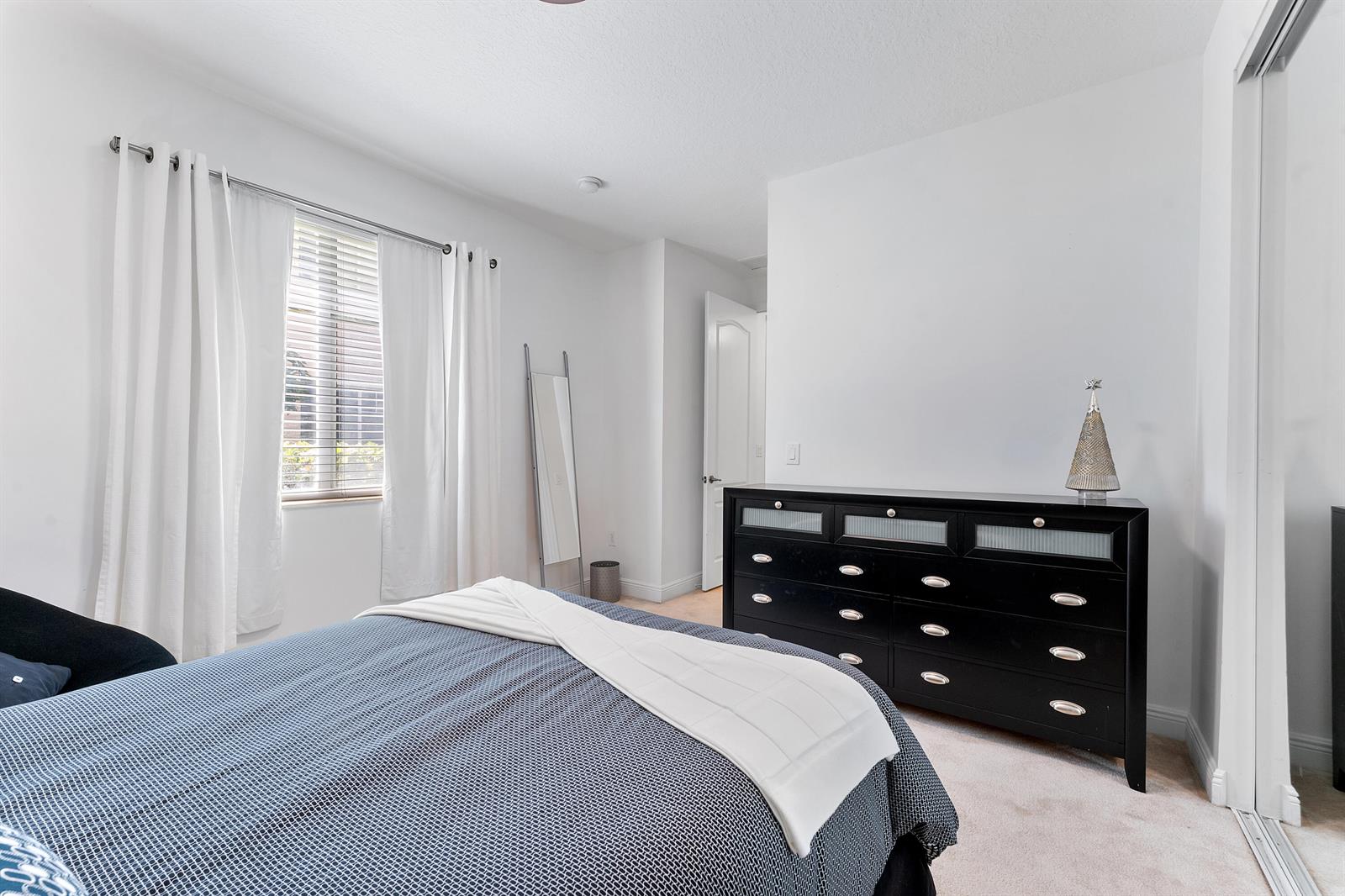 A bedroom features a bed with a blue patterned comforter, a black dresser, and curtains — 638 NW 38th Circle, Boca Raton FL 33431, BOCA RATON, FL