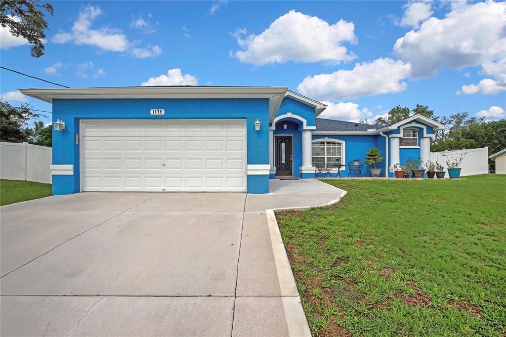 A bright blue single-story house features a two-car garage, white trim, and a concrete driveway — 1479 PIPER ROAD, SPRING HILL, FL