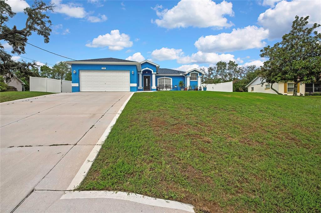 A blue single-story house with a white garage door and a concrete driveway — 1479 PIPER ROAD, SPRING HILL, FL