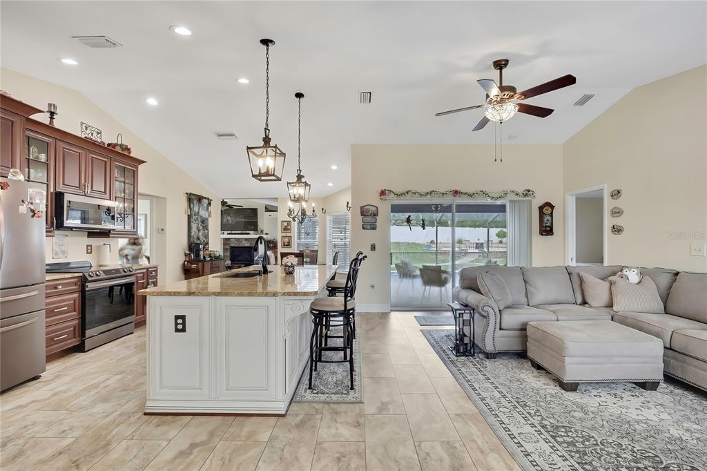 An open-concept kitchen and living area features a white island, dark cabinetry, and tile flooring — 1479 PIPER ROAD, SPRING HILL, FL