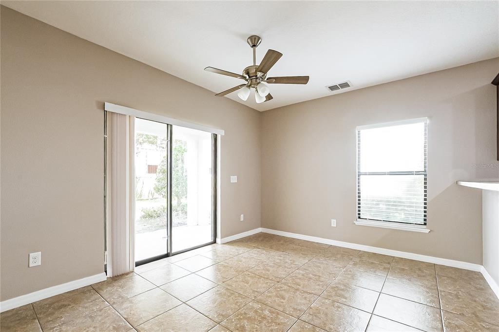 A dining area features tan walls, tile flooring, a ceiling fan, and sliding glass doors — 1310 WINDSOR LAKE CIRCLE, SANFORD, FL