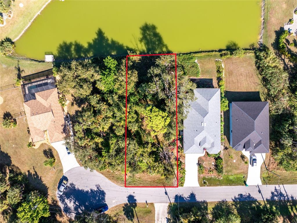 An aerial view shows a vacant, wooded residential lot outlined in red bordering a lake — 106 REBEL COURT, ROTONDA WEST, FL