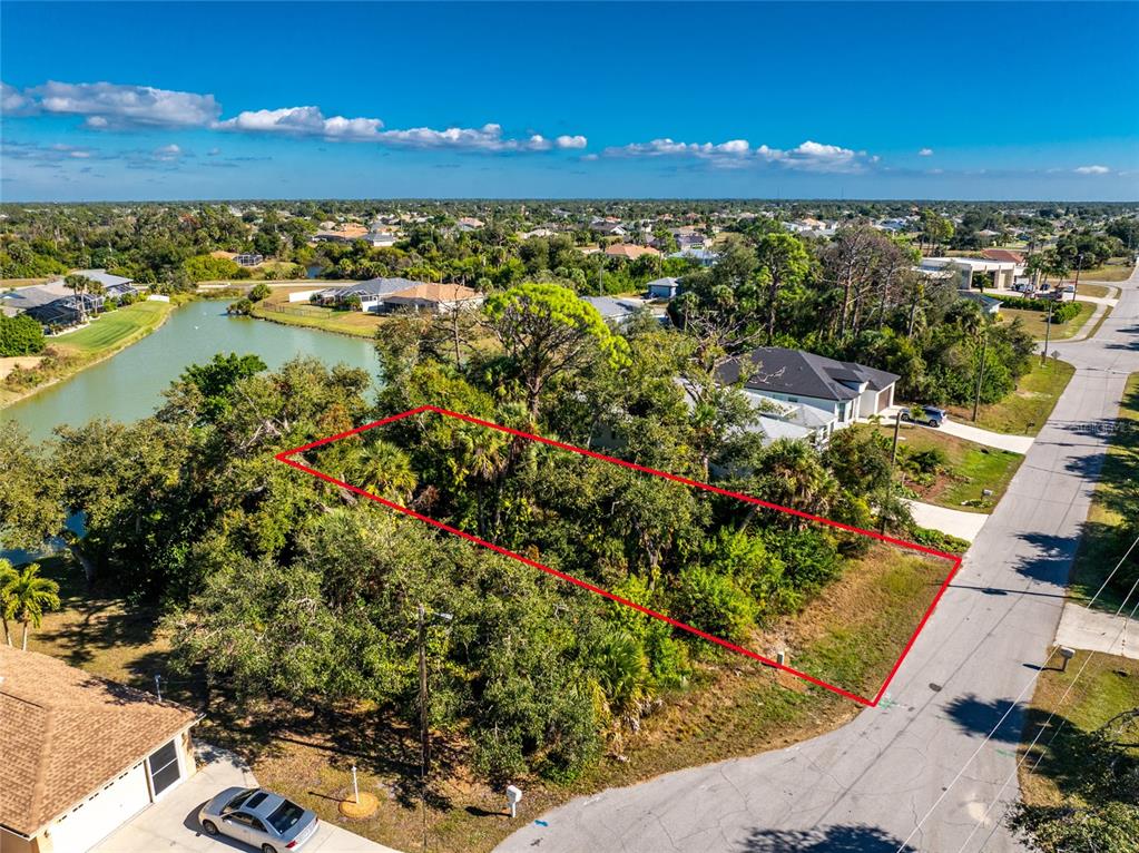An aerial view shows a vacant, wooded residential lot outlined in red next to a road — 106 REBEL COURT, ROTONDA WEST, FL