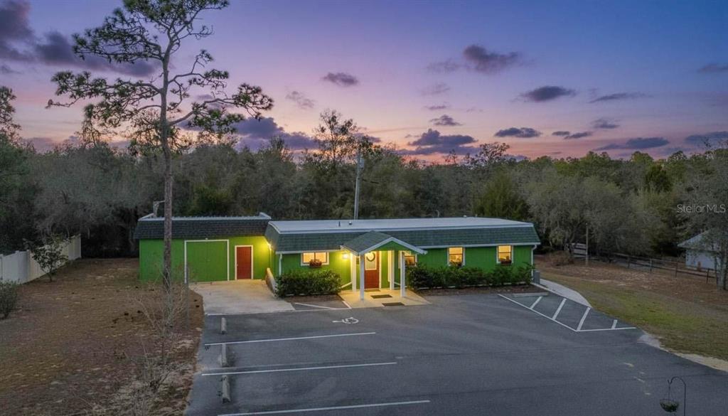 A green single-story building with a parking lot in front at sunset — 11840 N ANGUS HILLS TERRACE, DUNNELLON, FL