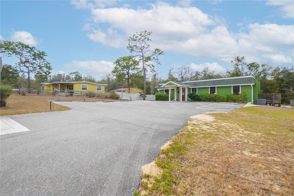 A paved parking lot sits in front of a green building and a yellow house — 11840 N ANGUS HILLS TERRACE, DUNNELLON, FL
