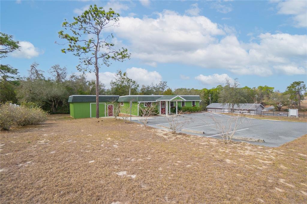 A green, single-story commercial building with a paved parking lot sits on a grassy lot — 11840 N ANGUS HILLS TERRACE, DUNNELLON, FL