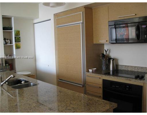 A kitchen features granite countertops, light wood cabinetry, a built-in refrigerator, and a black microwave — 1830 S Ocean Dr # 1505, Hallandale Beach FL 33009, HALLANDALE BEACH, FL